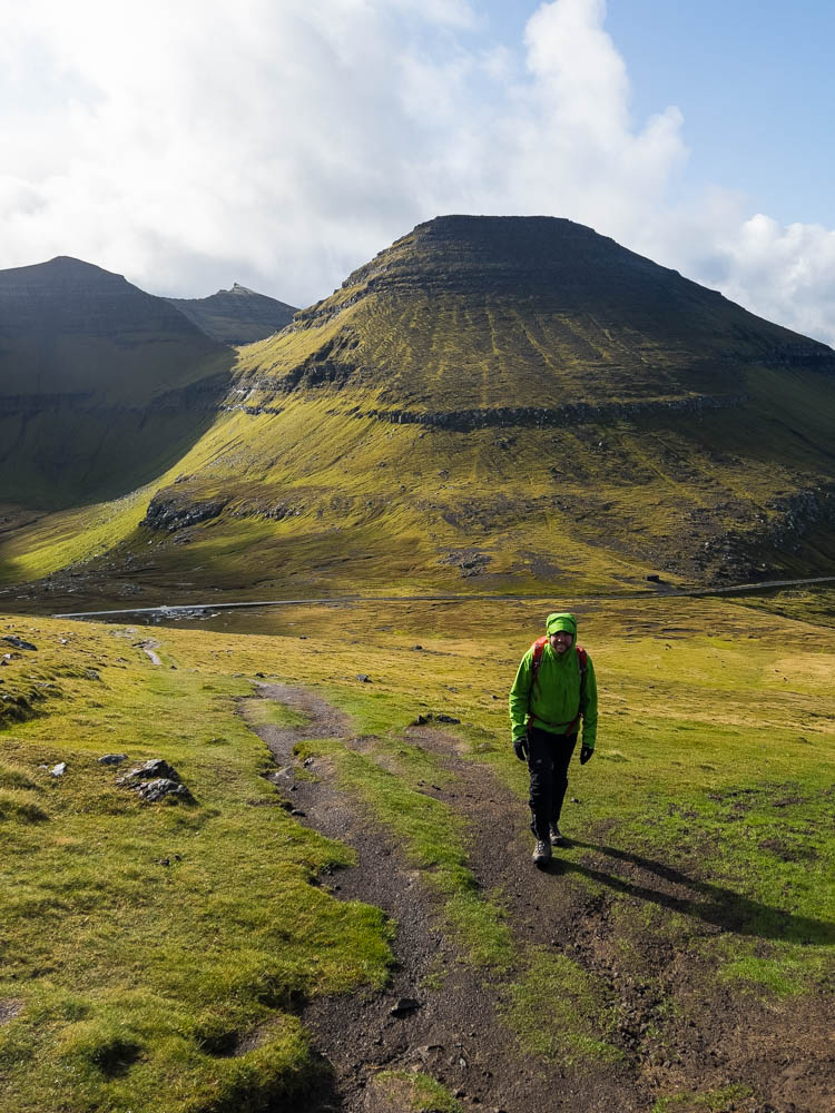 Julian beim wandern durch Graslandschaft auf den höchsten Gipfel der Färöer Slættaratindur.