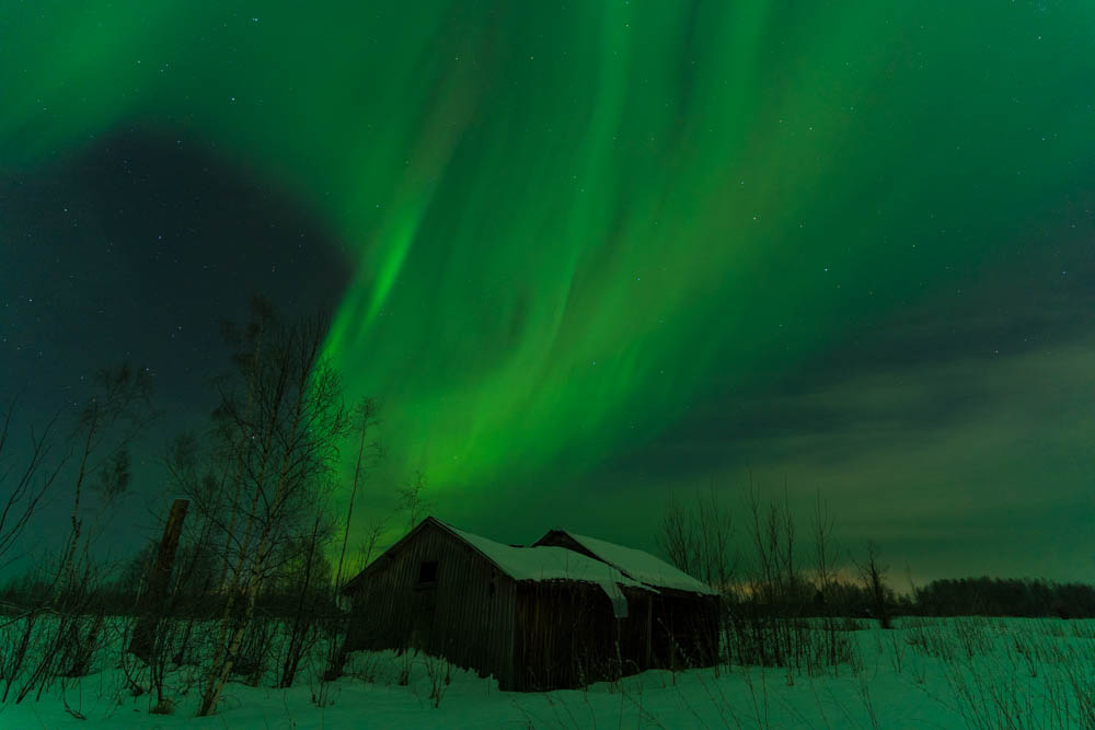 Polarlichter über zwei Hütten in Schweden im Winter