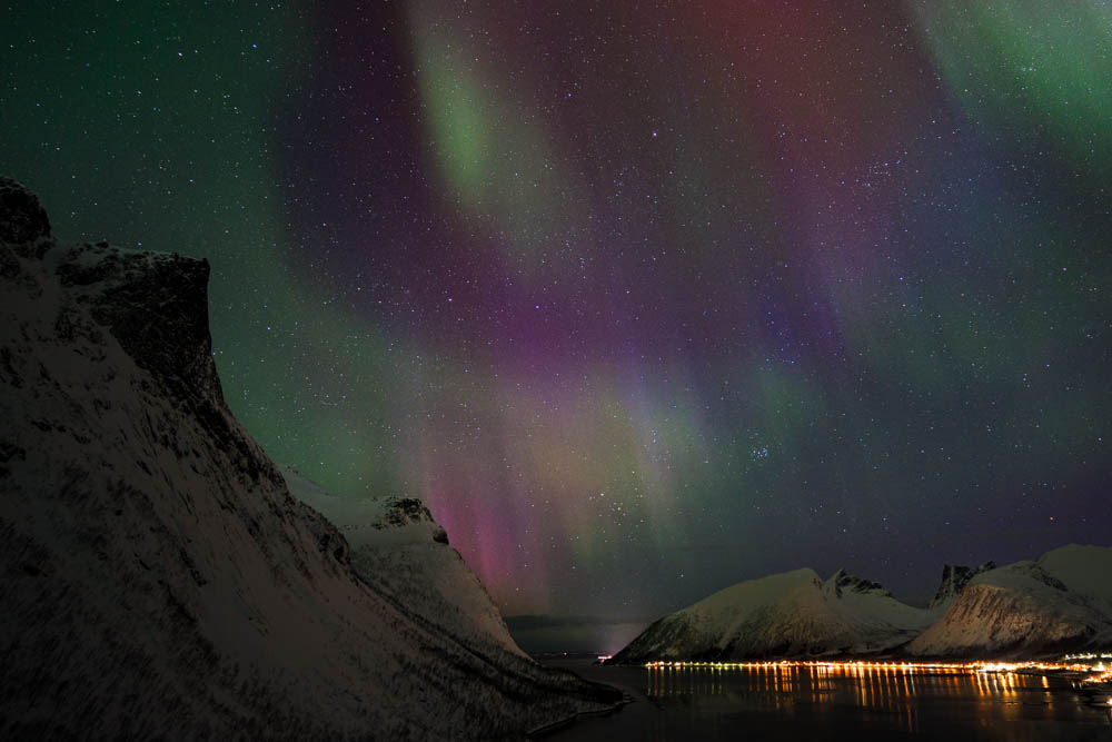 Blaue, violette und grüne Polarlichter über einem Fjord in Senja, Norwegen. Sternenhimmel und Faszination Nordlichter