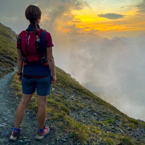 Melanie bei einer Wanderung mit Sonnenuntergang in den Alpen.