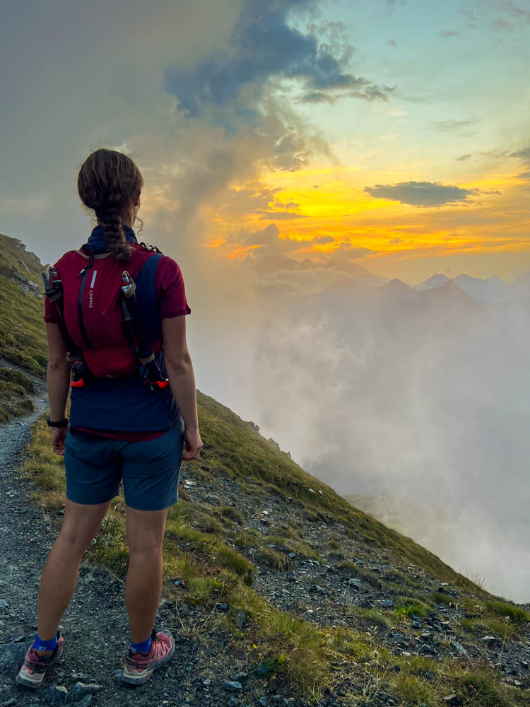 Melanie bei einer Wanderung mit Sonnenuntergang in den Alpen.