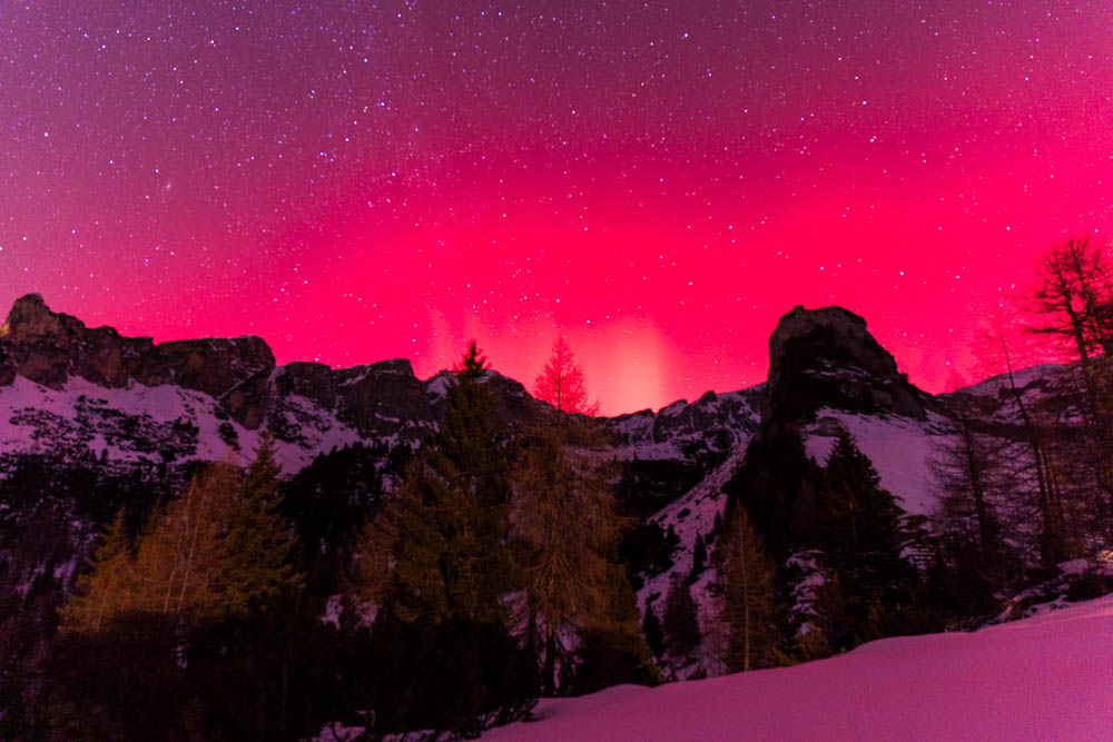 Polarlichter in den Alpen über dem Achensee. Der Himmel leuchtet violett über dem Rofangebirge.