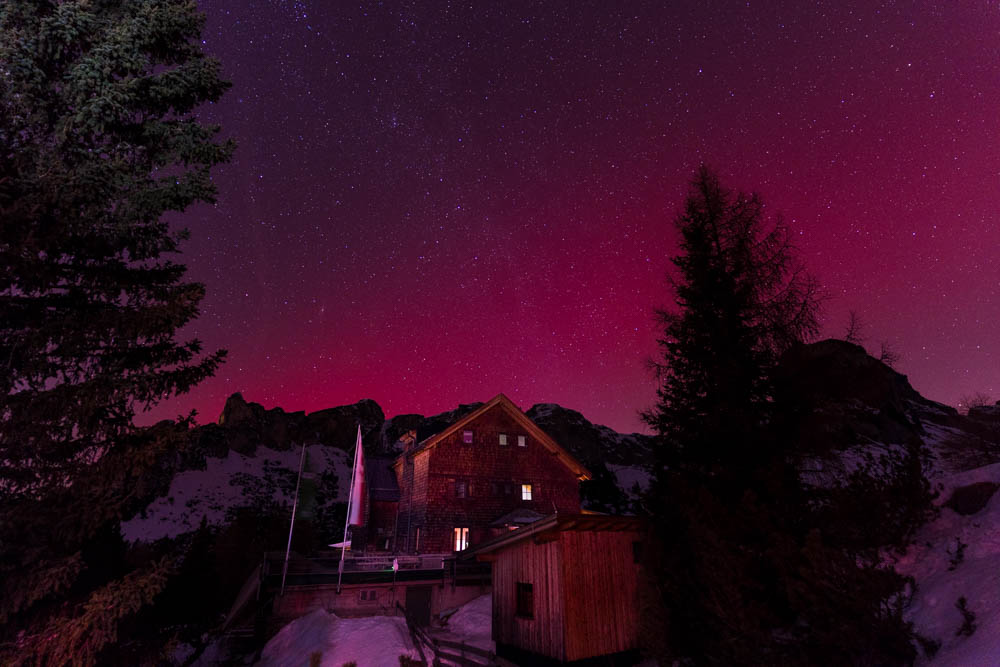 Polarlichter in den Alpen über dem Achensee. Der Himmel leuchtet violett über dem Rofangebirge und der Alpenvereinshütte Erfurter Hütte.